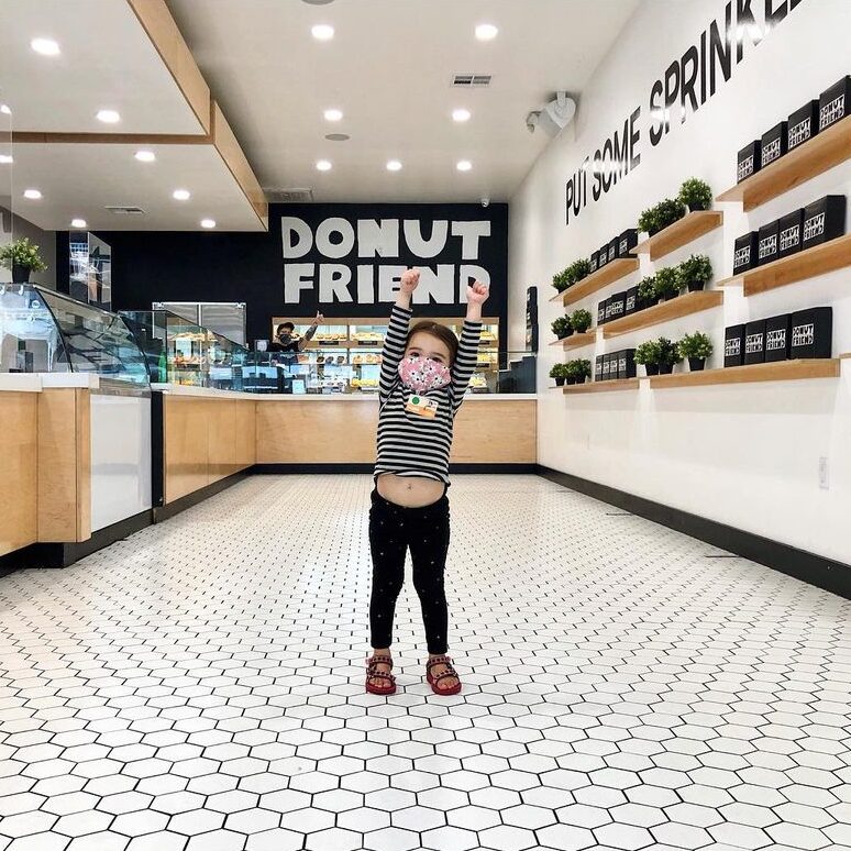 a kid standing inside DTLA Donut Friend