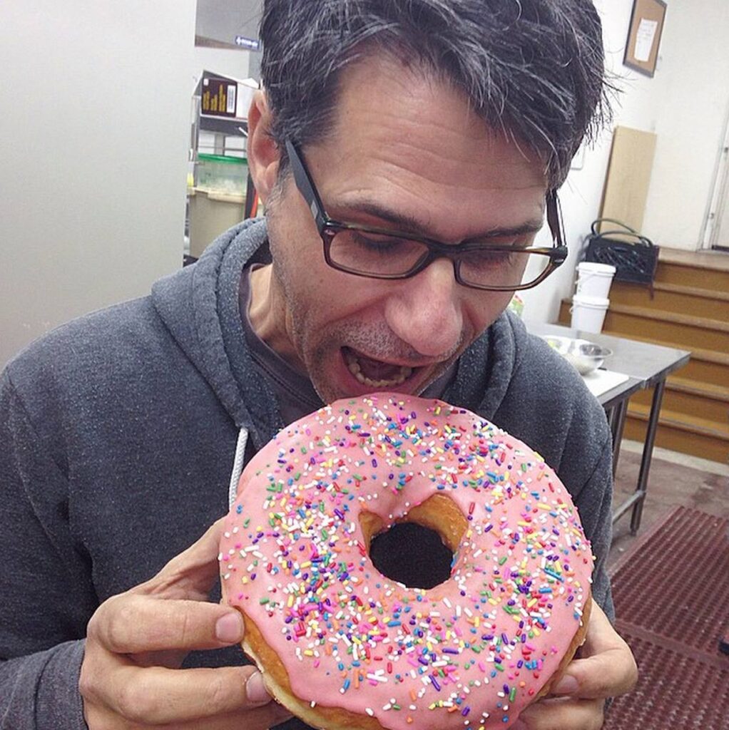 a man taking a bite out of a giant donut