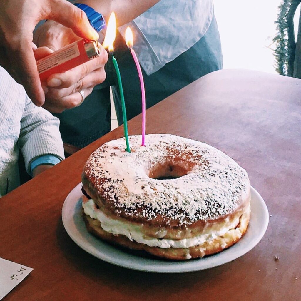 A giant donut with two candles being lit